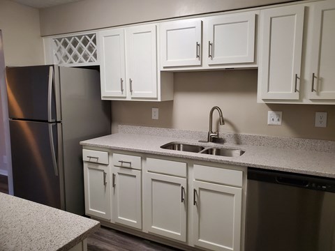 A kitchen with white cabinets and a black refrigerator.