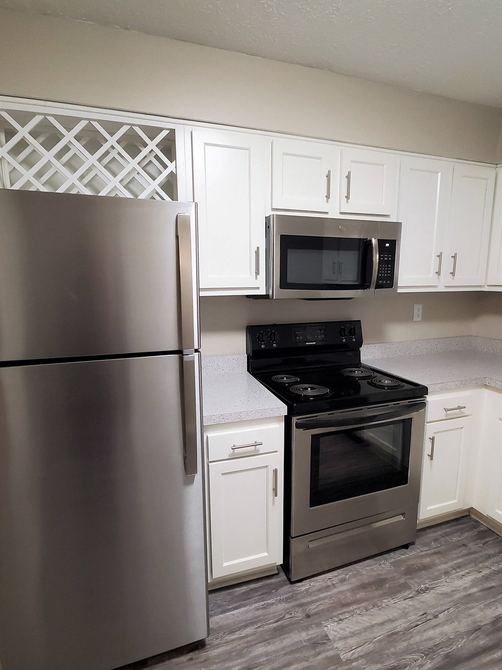 A kitchen with a stainless steel refrigerator, microwave, oven, and cabinets.