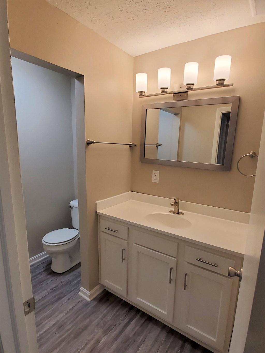 A bathroom with a toilet, sink, and mirror.