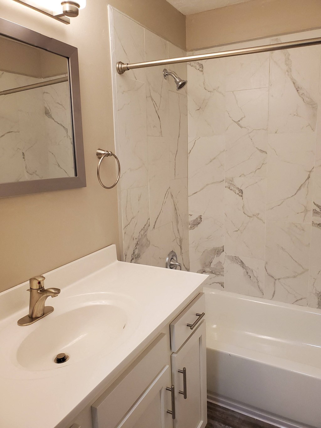 A white sink with a gold faucet in a marble tiled bathroom.