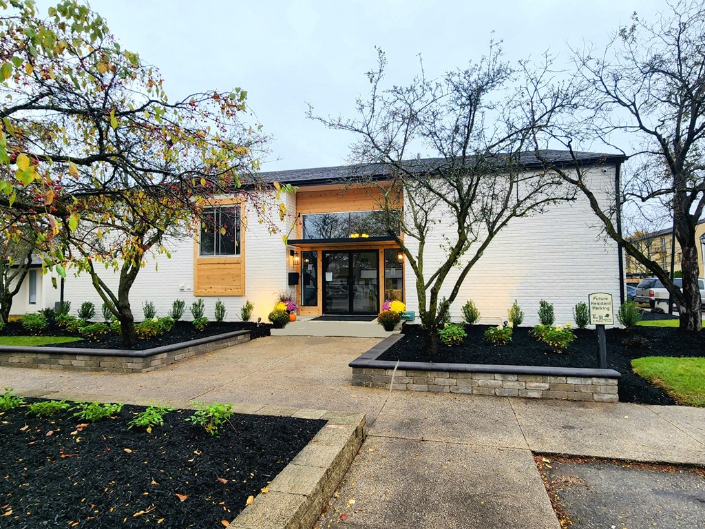 the front of a white house with a sidewalk and trees