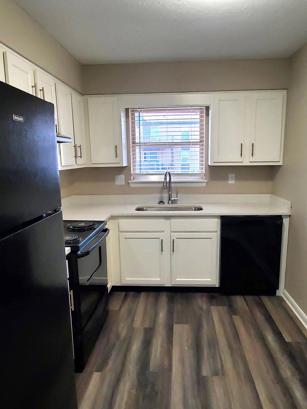 A kitchen with black appliances and white cabinets.