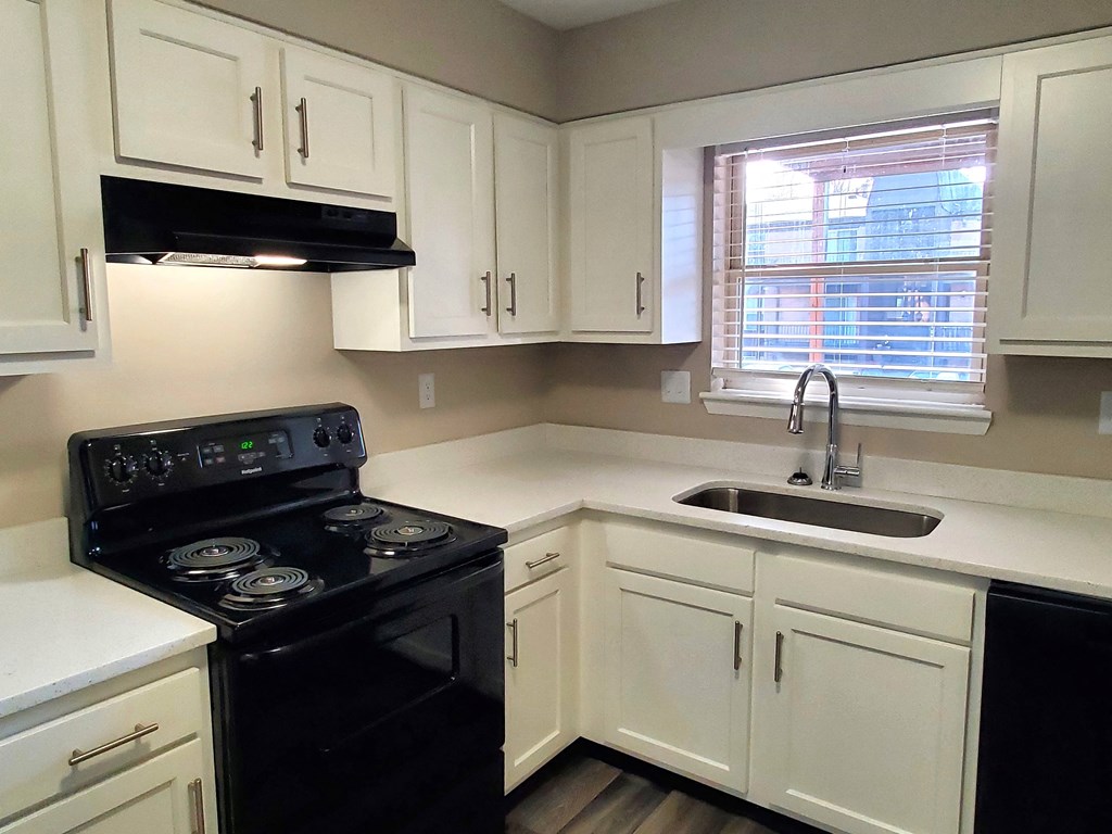 A kitchen with black appliances and white cabinets.