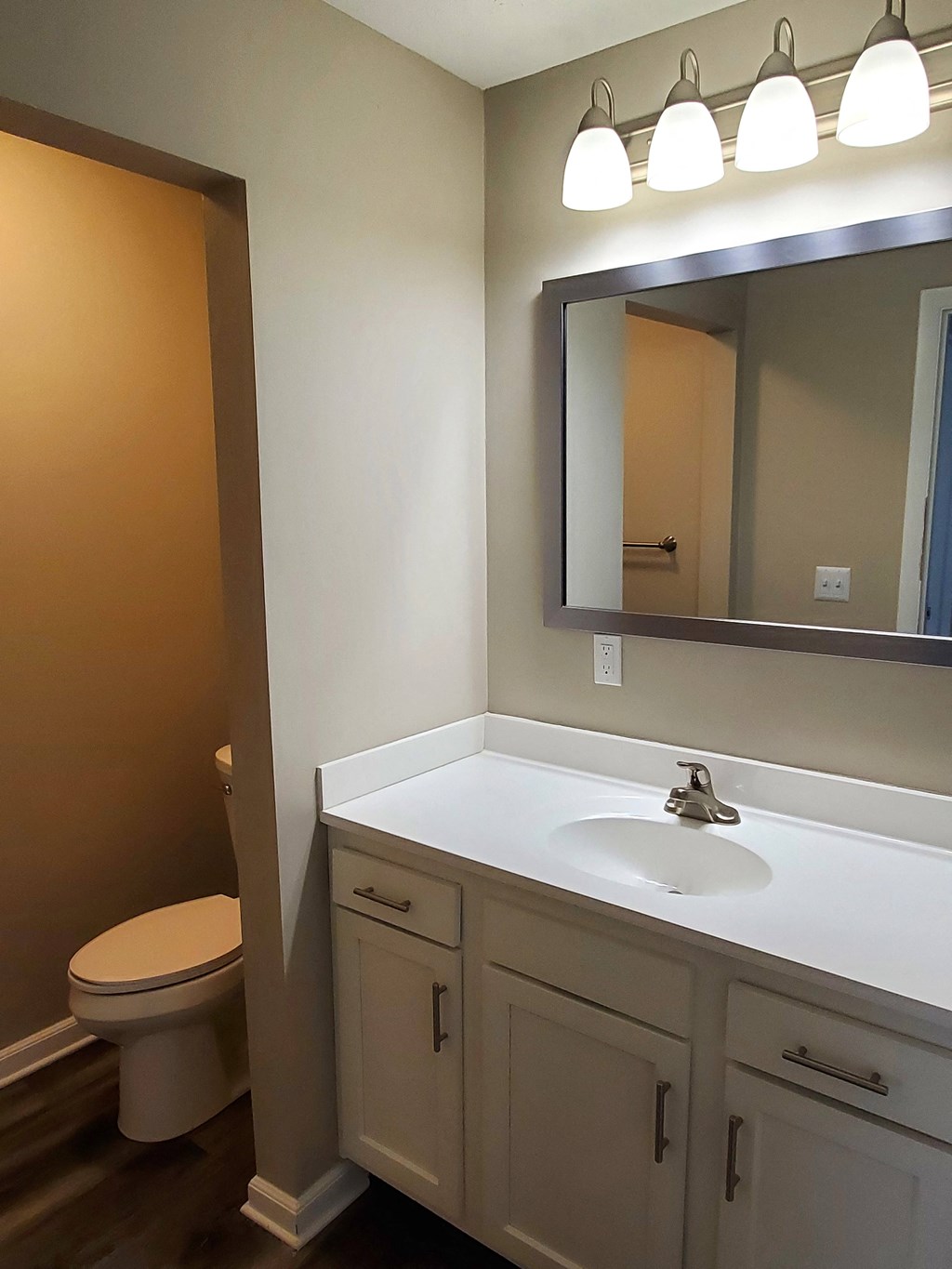 A bathroom with a toilet, sink, and mirror.