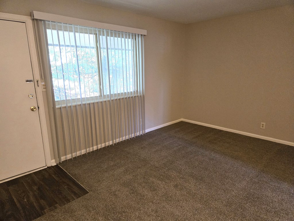 an empty living room with a window and a door
