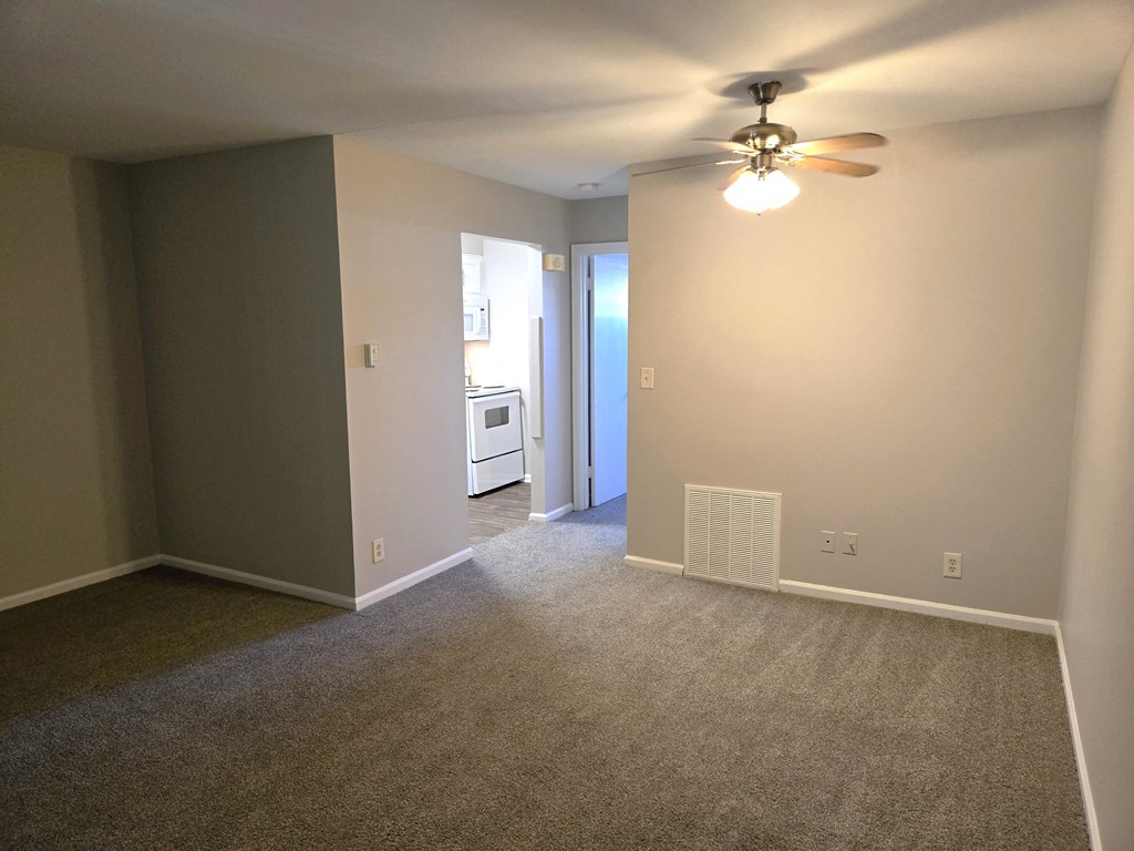 a living room with carpet and a ceiling fan