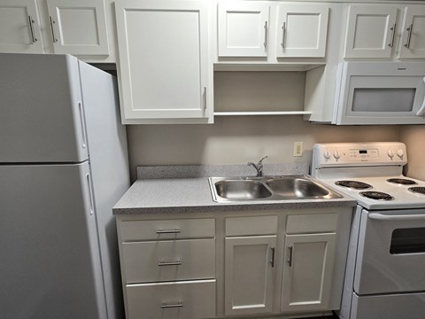 A kitchen with white cabinets and appliances.