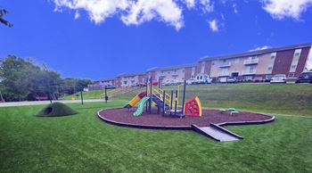 a playground in a park in front of an apartment building
