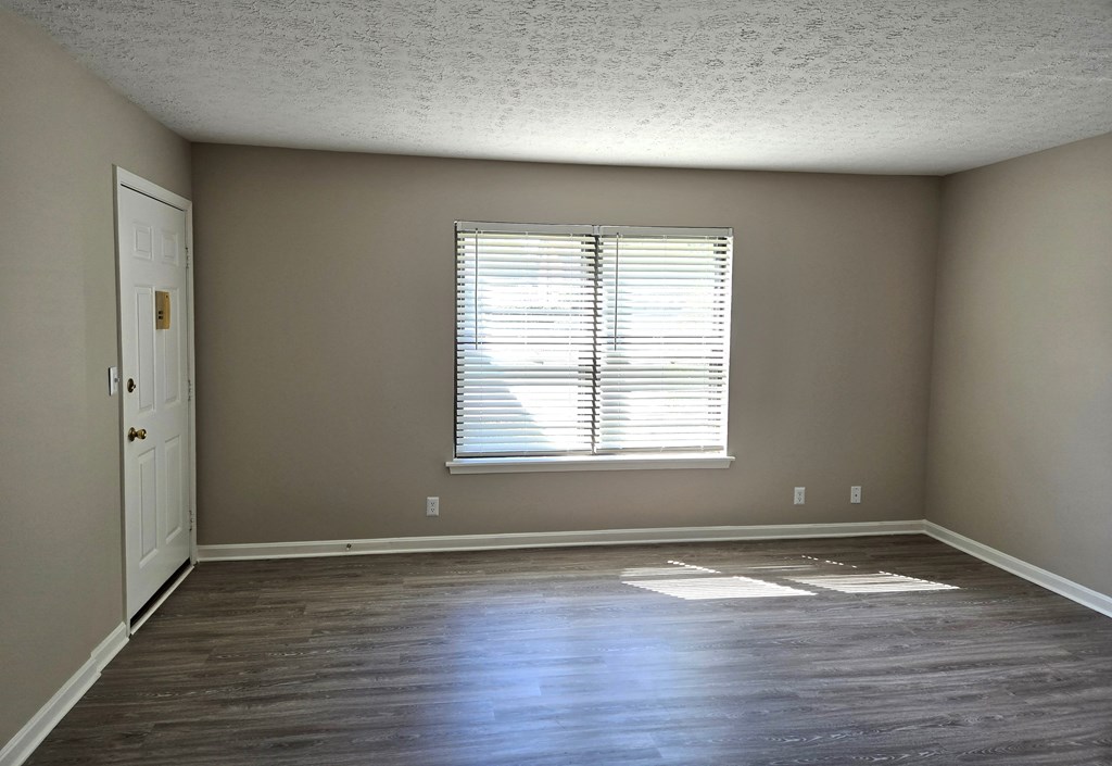 an empty living room with wood floors and a window