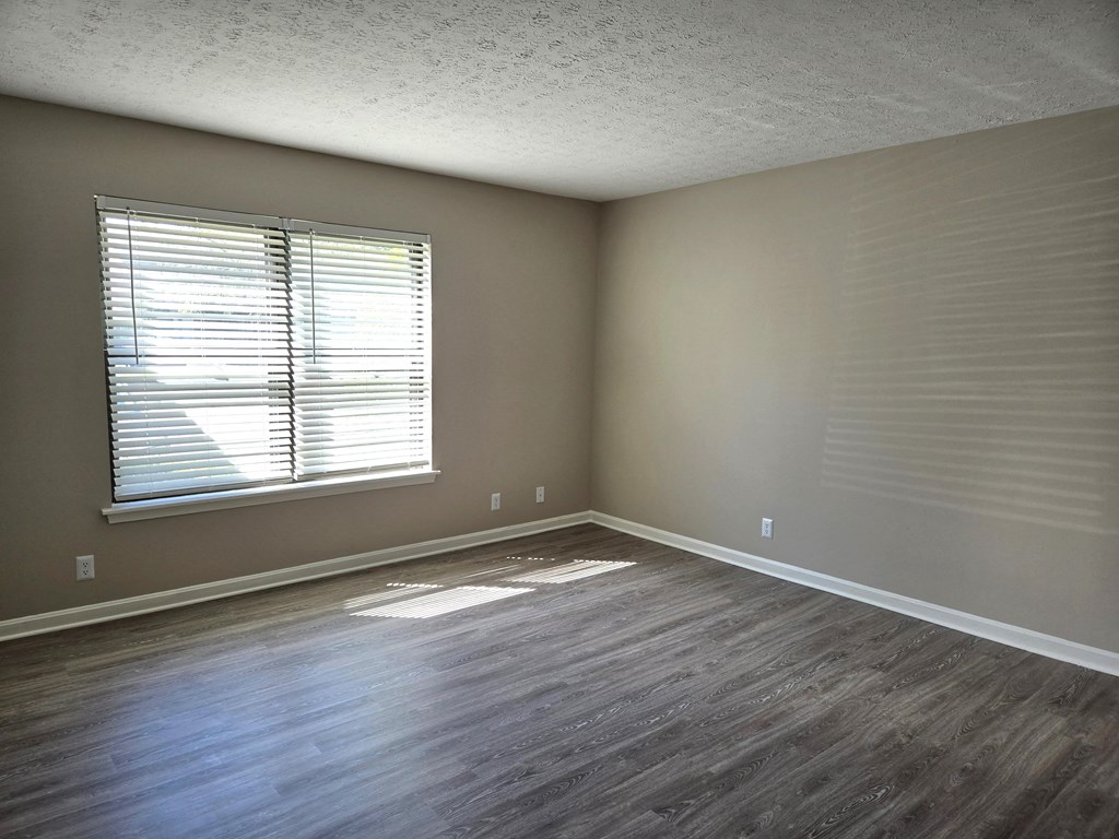 an empty living room with wood floors and a window