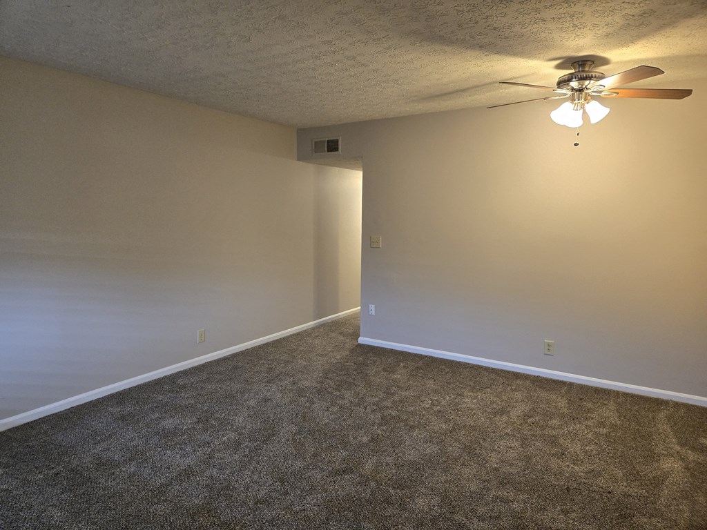 A room with a ceiling fan and carpeted floor.