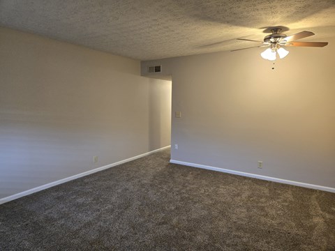 A room with a ceiling fan and carpeted floor.