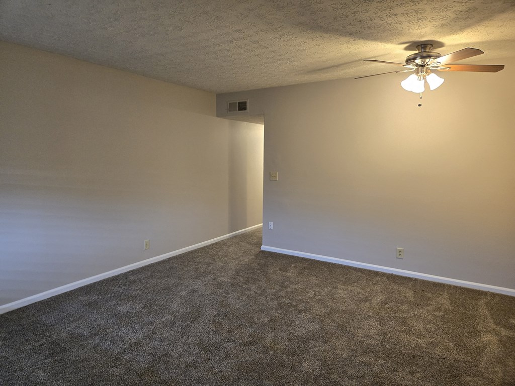 an empty living room with a ceiling fan