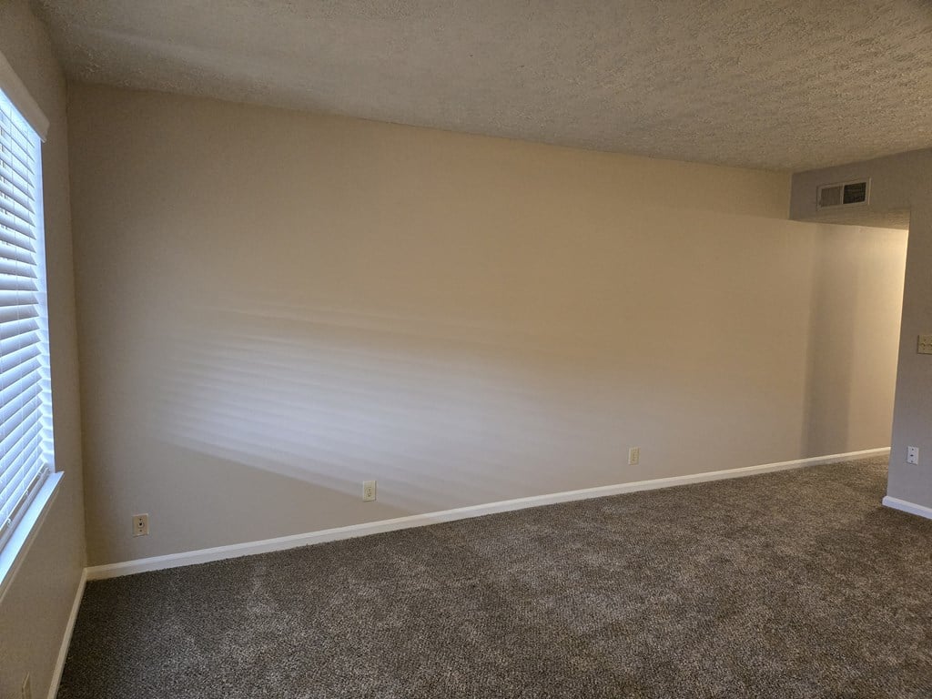 an empty room with a white wall and a window