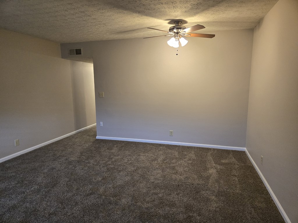 A room with a ceiling fan and carpeted floor.