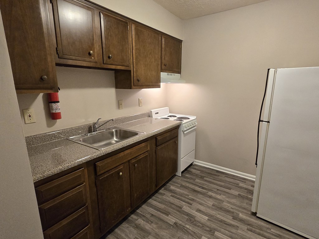 A kitchen with a white fridge and wooden cabinets.