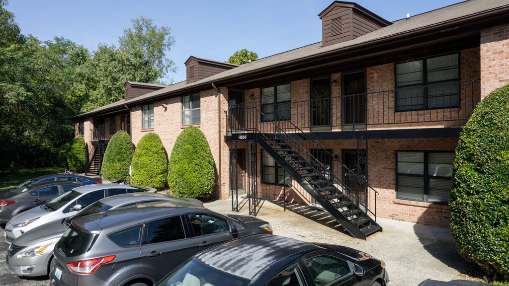 an apartment building with a parking lot full of cars