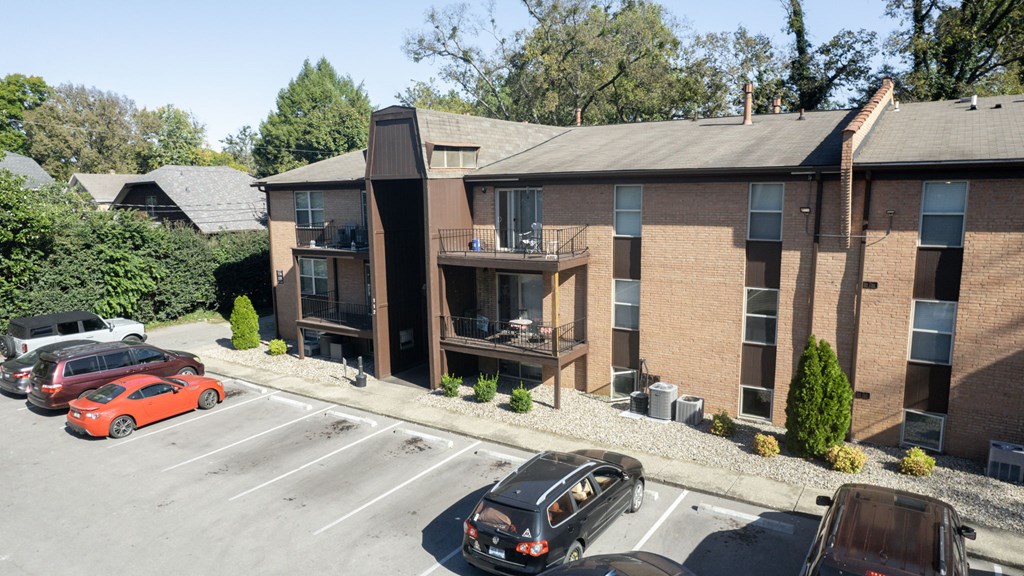 an aerial view of a brick apartment building with cars in a parking lot