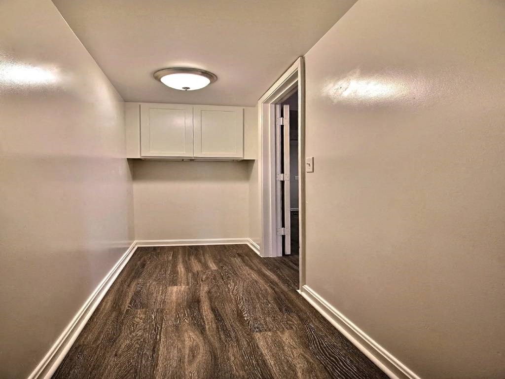 an empty room with a door to a kitchen and a closet
