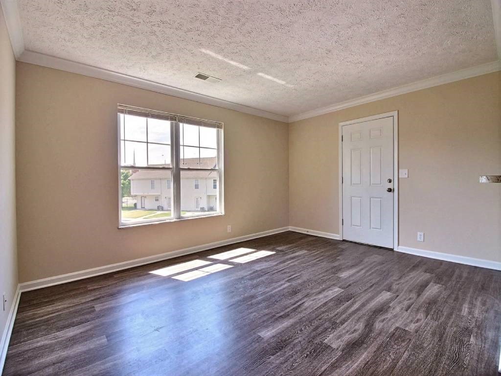 an empty living room with wood floors and a window