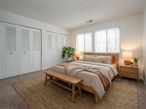 A bedroom with a bed, nightstand, and a rug.