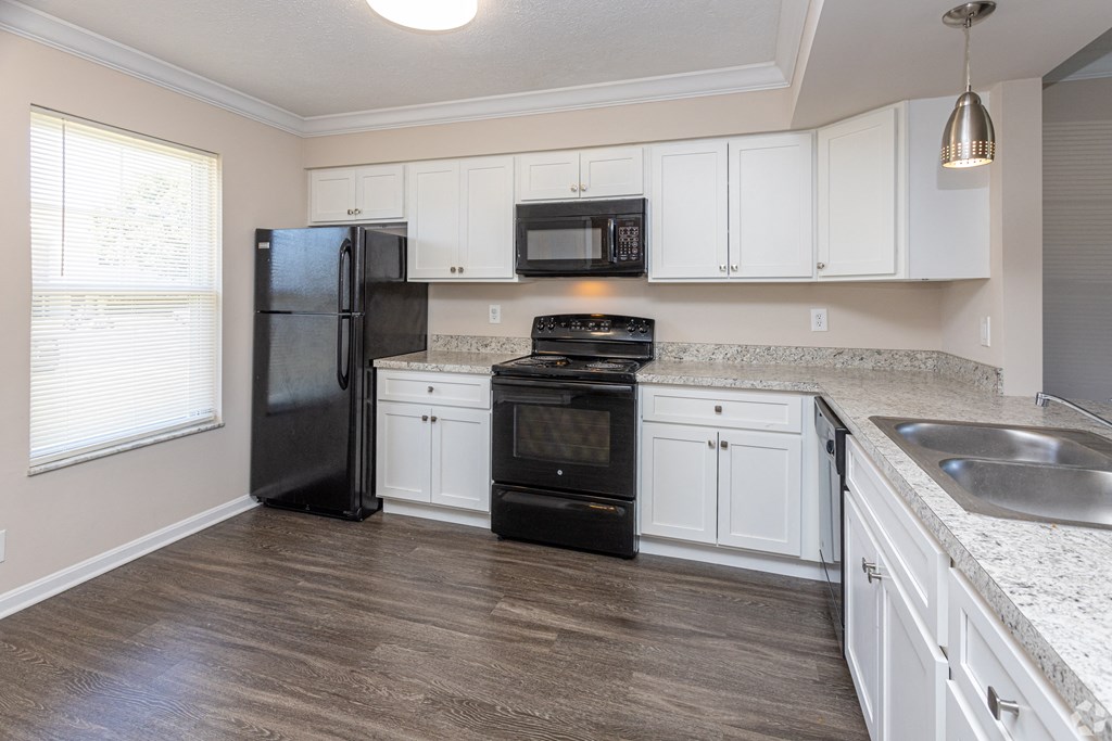 an empty kitchen with white cabinets and black appliances