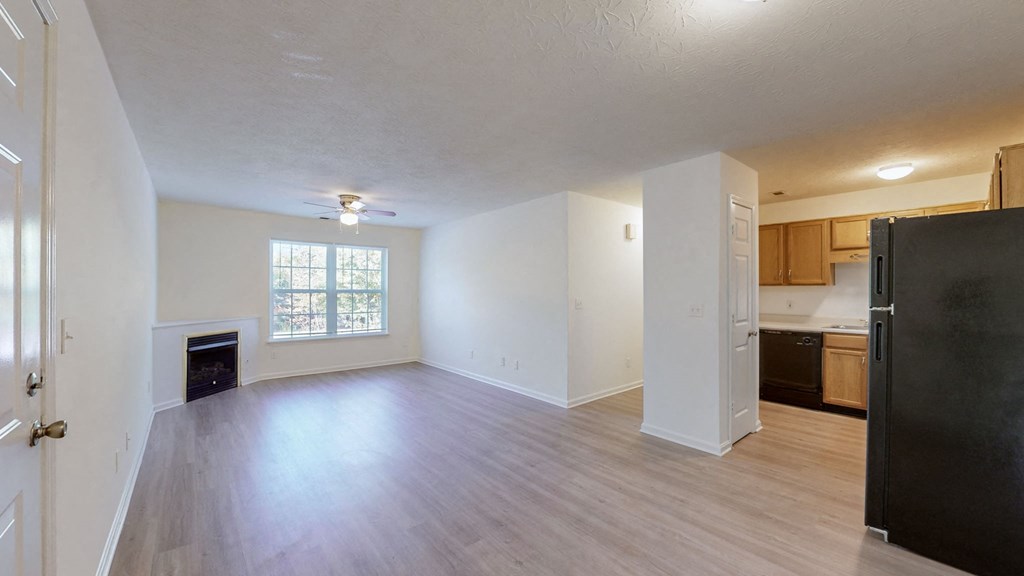 an empty living room and kitchen with wood flooring and a window