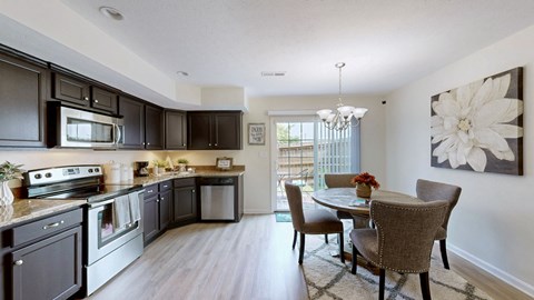 A kitchen with dark brown cabinets and a dining table with chairs.