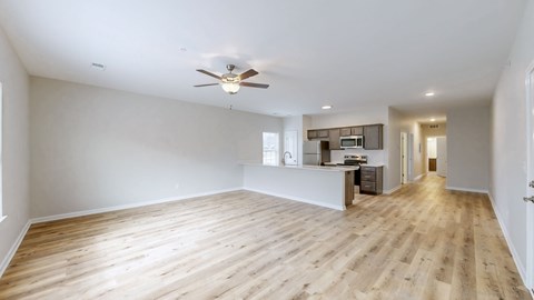 A spacious room with a ceiling fan and wooden flooring.
