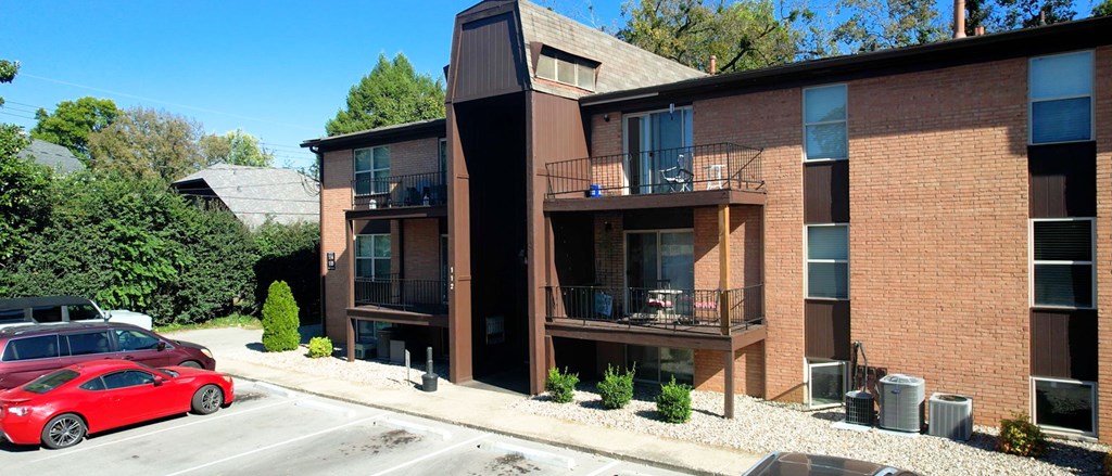 A red car is parked on the street in front of a building.