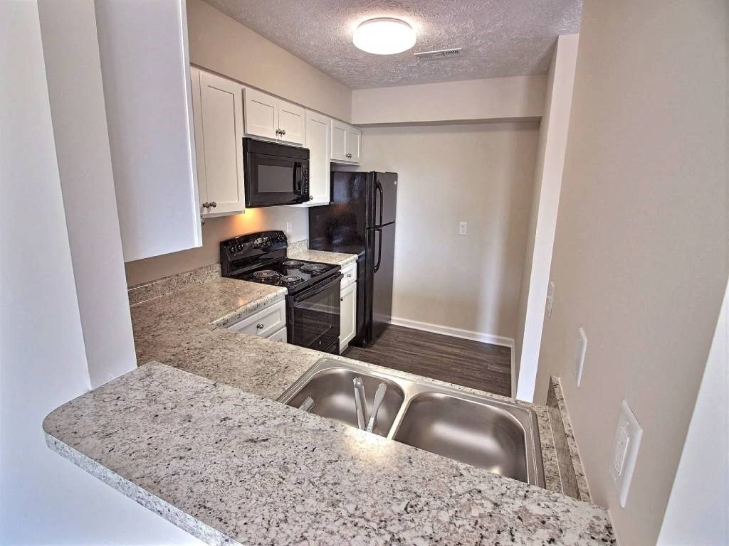 a kitchen with granite counter tops and a black refrigerator