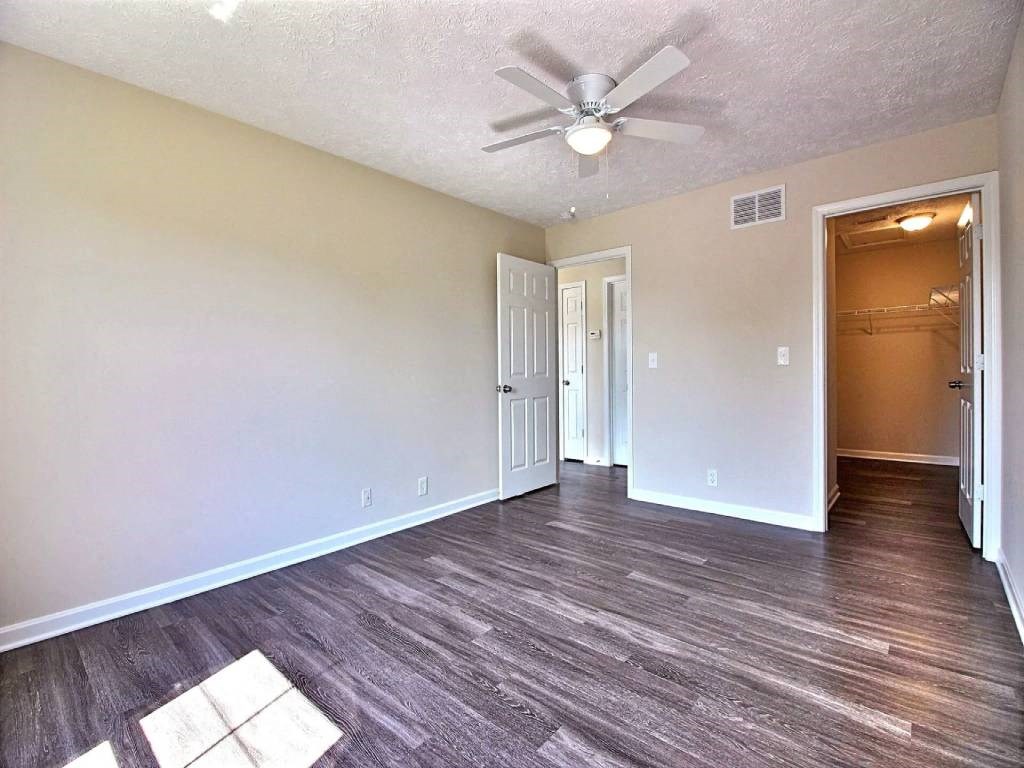 an empty living room with a ceiling fan and a door to a closet