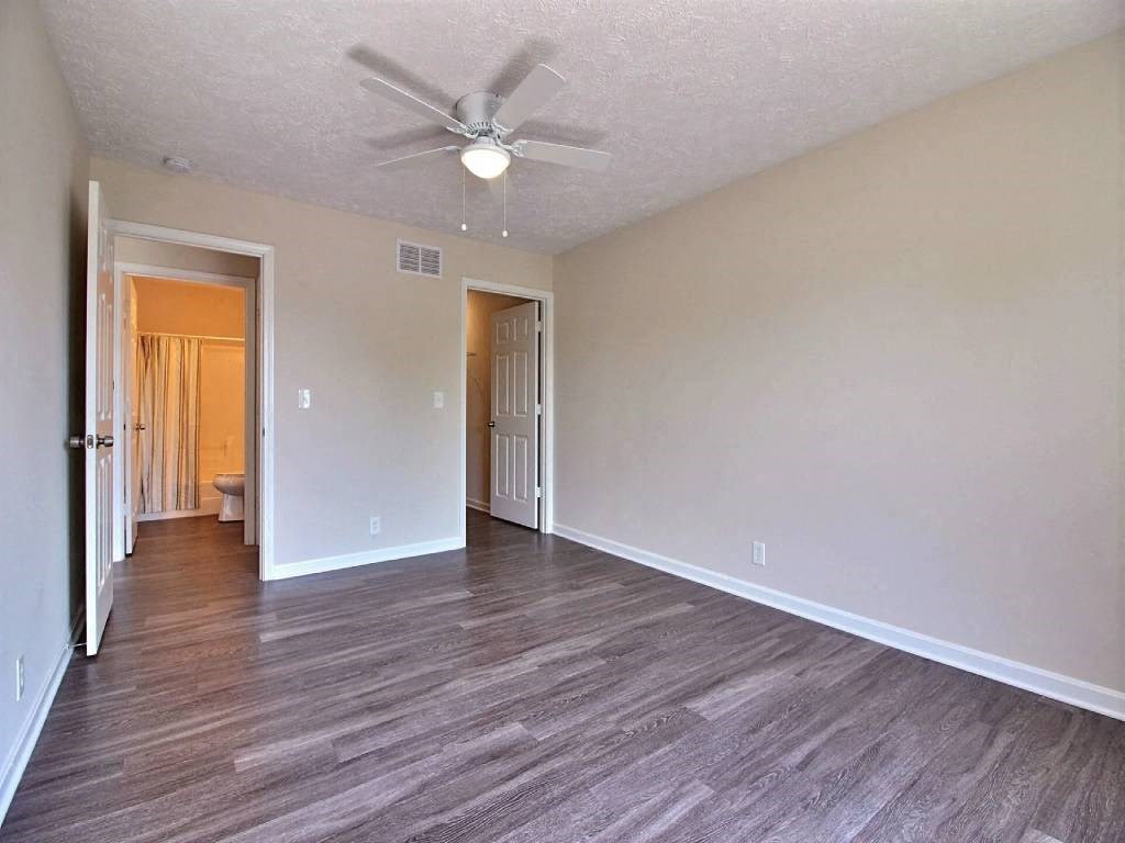 an empty living room with a ceiling fan and wood floors