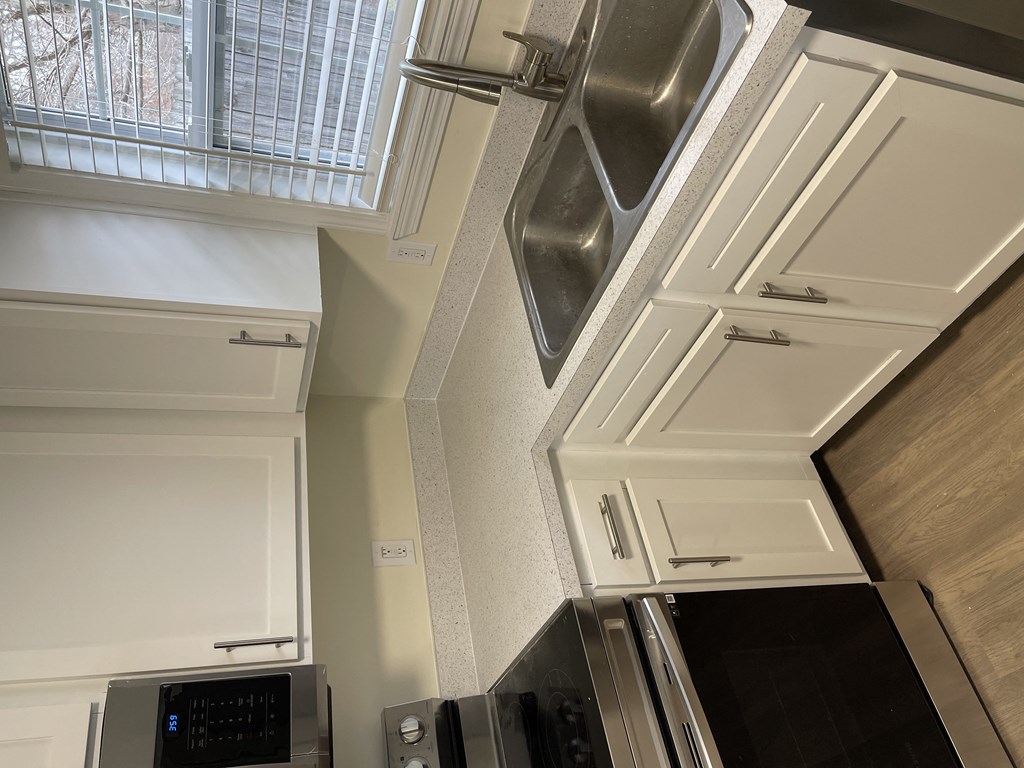 a kitchen with white cabinets and stainless steel appliances and a window