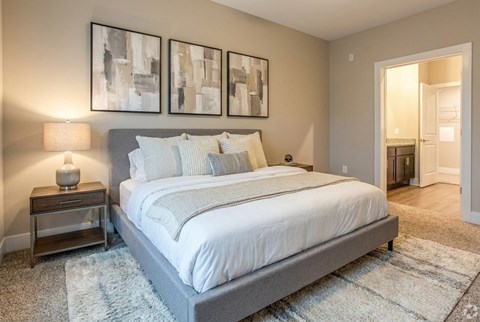 A bedroom with a large bed and two framed pictures on the wall.
