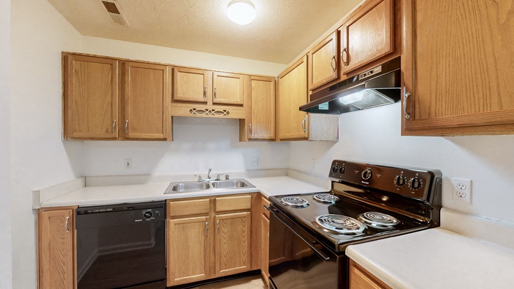a kitchen with wood cabinets and black appliances and white counter tops