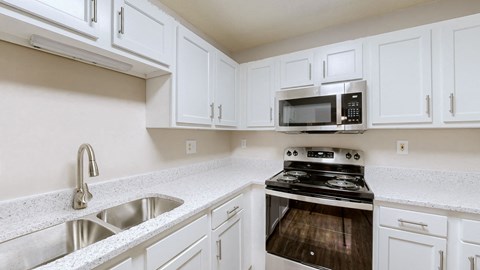 A kitchen with white cabinets and a stainless steel sink.