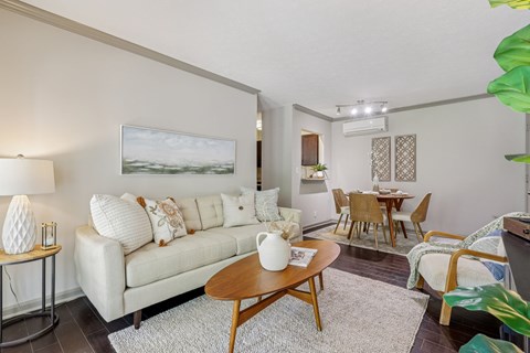 A living room with a white couch and a painting on the wall.