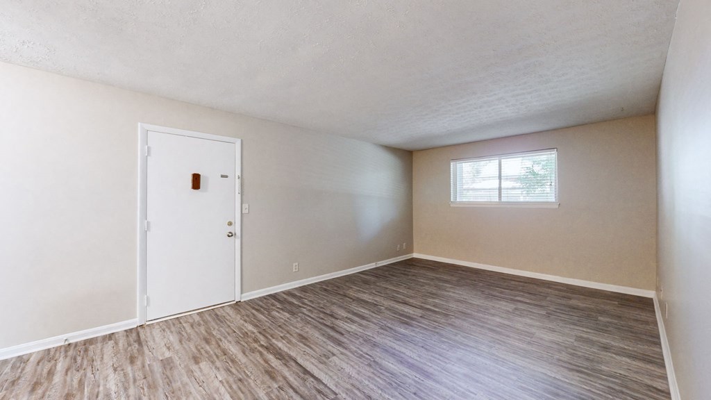an empty living room with a door and a window