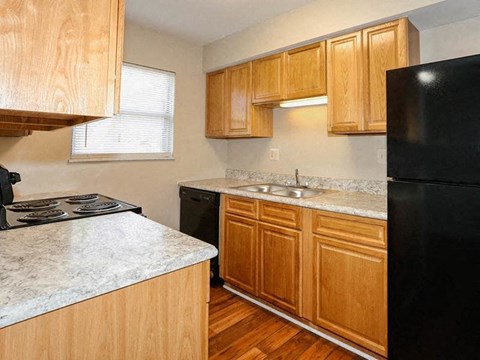 a kitchen with wooden cabinets and a black refrigerator