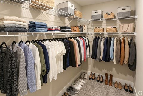 A well organized closet with clothes and shoes.