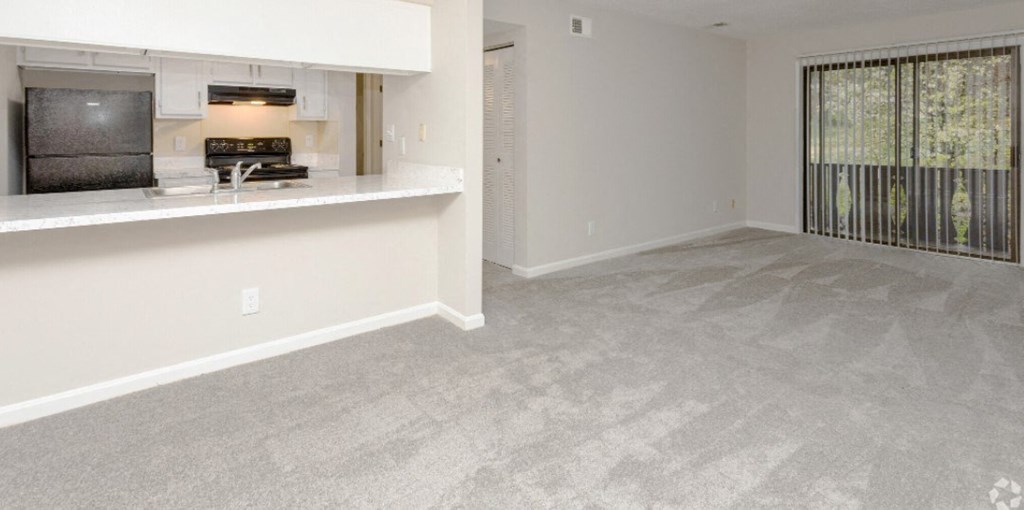 an empty living room and kitchen with a large window