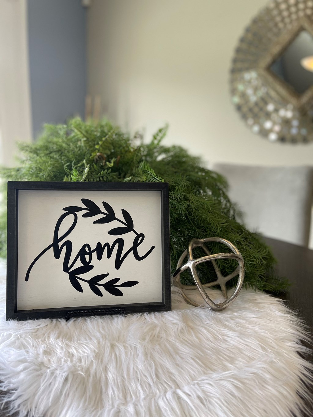 a faux fur pillow with a picture frame and a christmas arrangement on a table