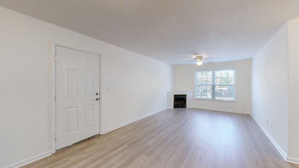 an empty living room with white walls and a window and a white door