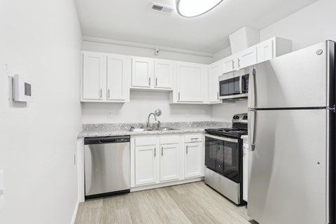 A kitchen with white cabinets and a black fridge.