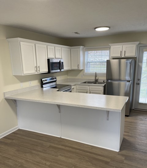 A kitchen with white cabinets and a white island.