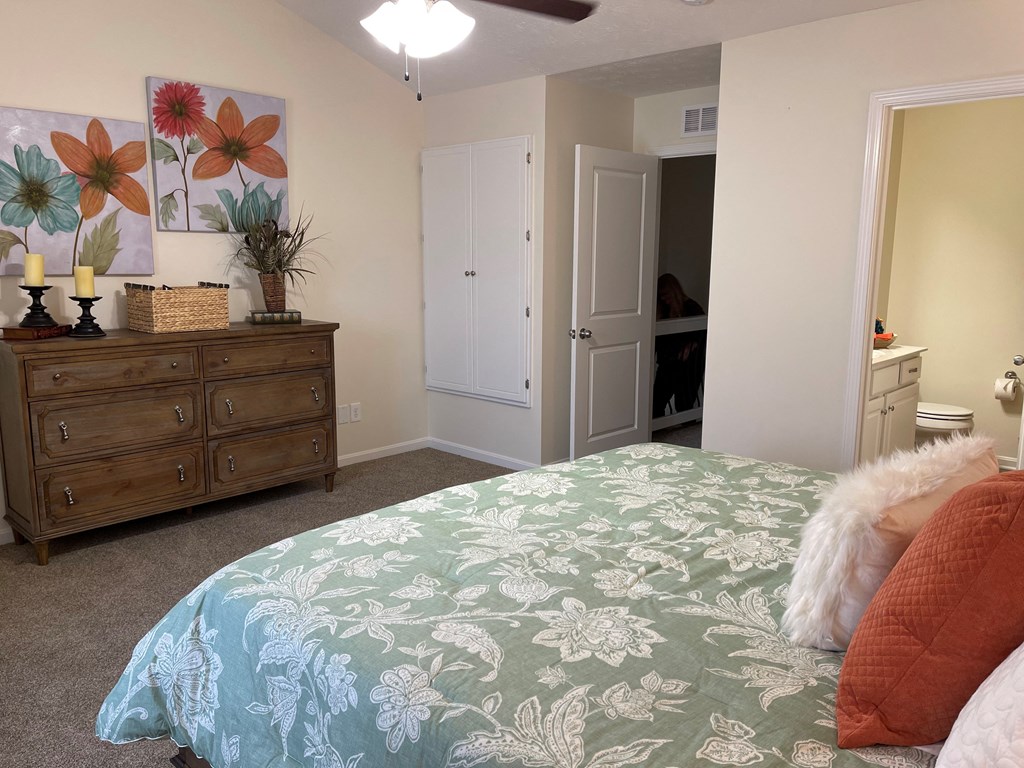 a bedroom with a bed and a dresser and a door to a bathroom