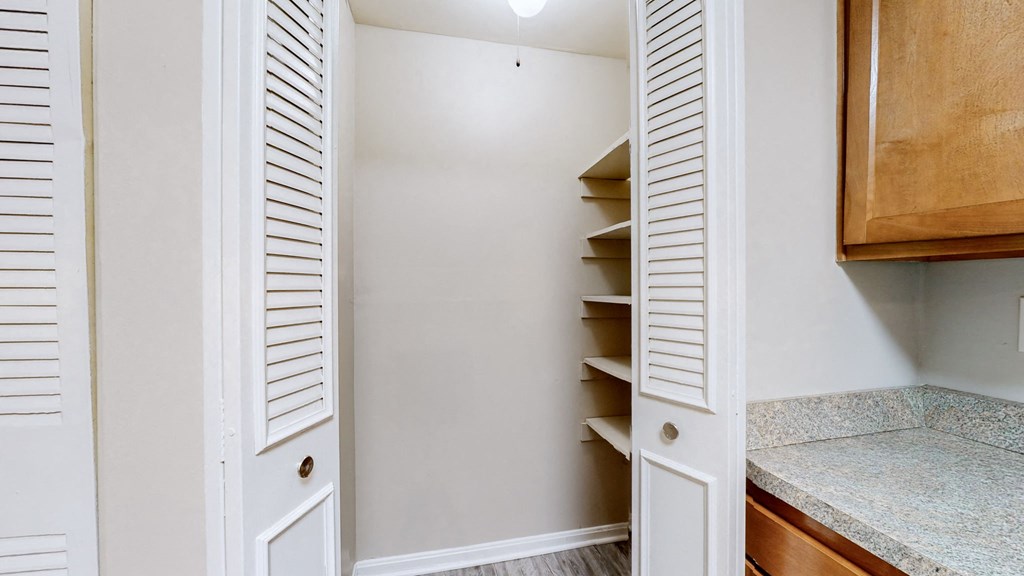 a walk in closet in a bathroom with white walls and shelves