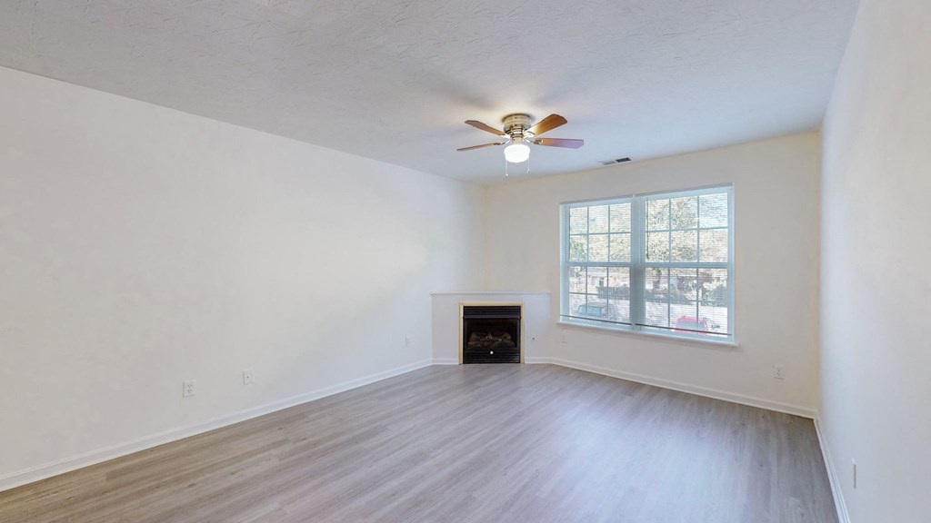 an empty living room with a ceiling fan and a window