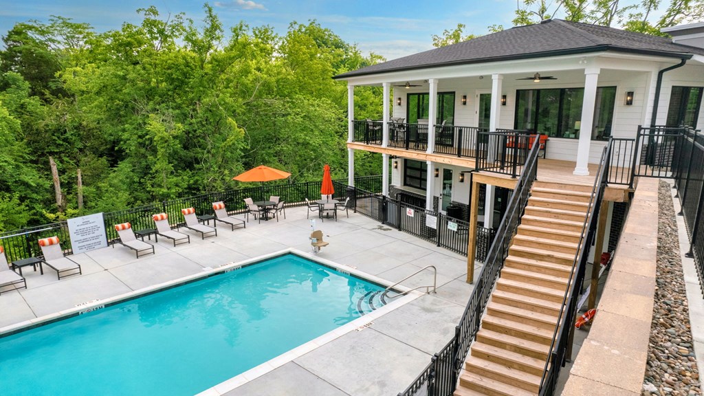 a swimming pool in front of a house with a pool and a porch